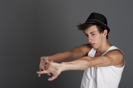 Young man in a white t-shirt with a black hat on a gray background in the Studioの写真素材