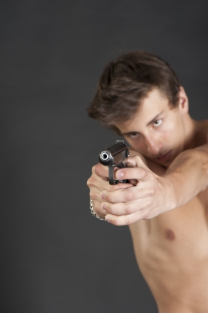 Young guy with a gun in the Studio on a black backgroundの写真素材