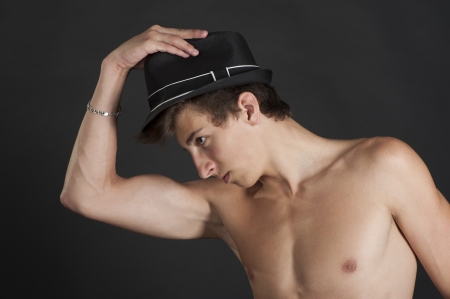 Young guy with the black hat on your head on a black background in the studioの写真素材