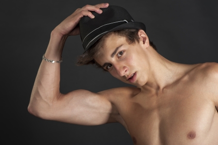 Young guy with the black hat on your head on a black background in the studioの写真素材