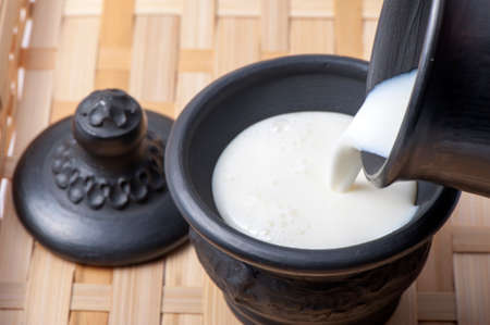 Milk is poured into a cup on the tableの写真素材