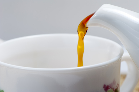 Black tea is poured into the cup on the tableの写真素材