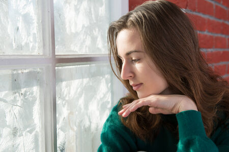 Portrait of a young attractive woman at a window in the brightの写真素材