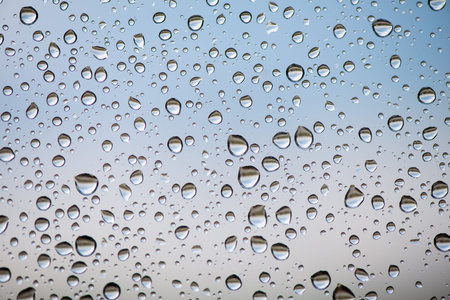 Different sized raindrops on glass close up