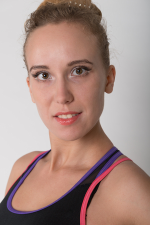 A young blonde in a gym for sports top on a light backgroundの写真素材