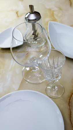 Still life with white dining utensils, glasses on a marble countertopの写真素材