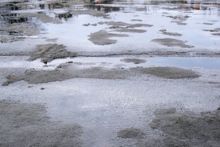 Background of urban asphalt wet road with snow in winterの写真素材