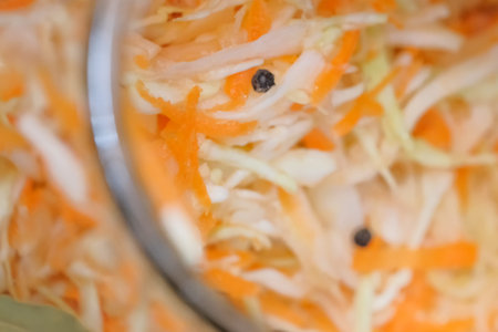 Shredder cabbage for pickling with carrots and spices in a glass jar in a city apartment, close-upの写真素材