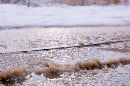 Paved road covered with melting snow in poor condition in a city courtyard winter study, close-up