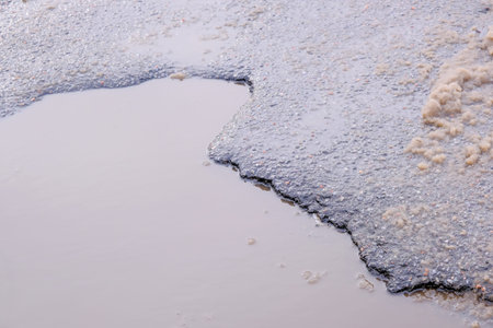 Paved road covered with melting snow in poor condition in a city courtyard winter study, close-up