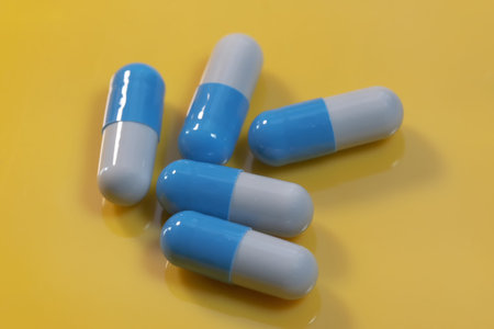 Blue gelatin soluble capsules with medicinal powder on a yellow background close-up macro photo