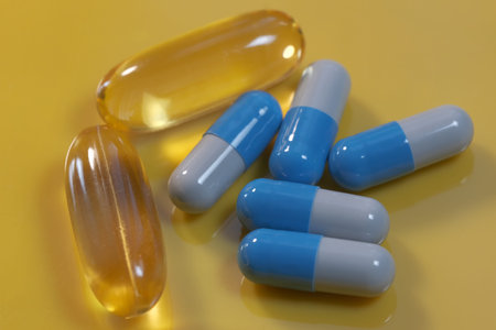 Yellow gelatin soluble capsules with vitamin omega three and blue on a yellow background close-up...