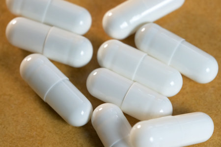 White gelatin soluble capsules with medicinal powder on a brown background close-up macro photo