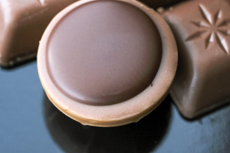 Chocolate still life with sweets and cookies with nuts close-up on a dark mirror background macro...