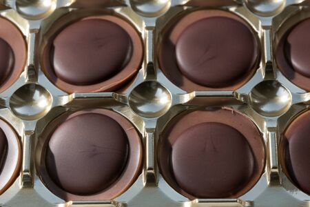 Chocolate candies with nut filling close-up on a dark mirror background macro photoの写真素材