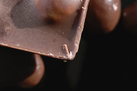 A bar of dark dark chocolate with whole hazelnuts closeup grocery background macro photography