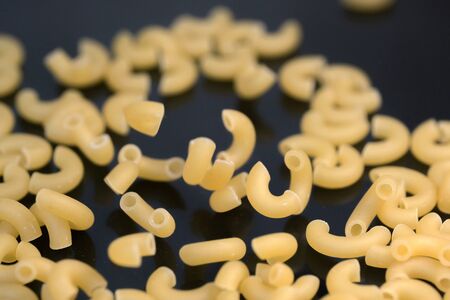 Small pasta made from premium wheat flour and eggs fall on a dark table surface close-up grocery background macro photographyの写真素材