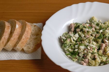 Vegetable salad with sausage, boiled eggs and potatoes, cucumbers, radishes, parsley and dill. It is used with bread kvass and sour cream as a cold first course.の写真素材