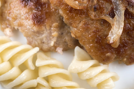 Tasty fresh hot meat cutlet from a mix of beef, pork and chicken fried with onions close-up with...