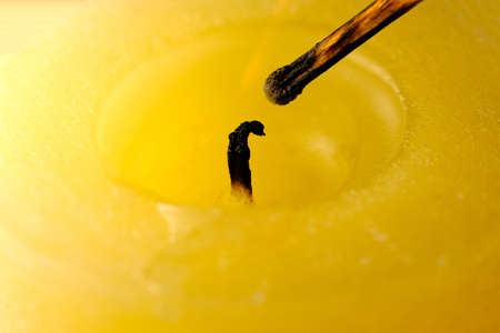Extinguished thick commemorative yellow candle on a black background close-up macro photographyの写真素材
