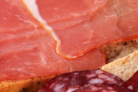 A sandwich with raw smoked sausage on a black background close-upの写真素材