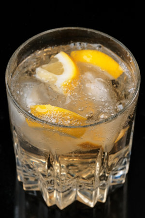 Lemonade drink with lemon and ice slices in a transparent crystal glass close-up macro photographyの写真素材
