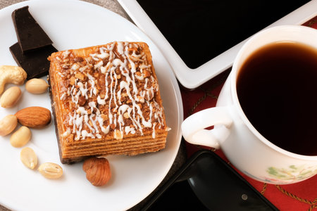 A cup of strong black tea with a tablet and glasses in a case on a red table close-up