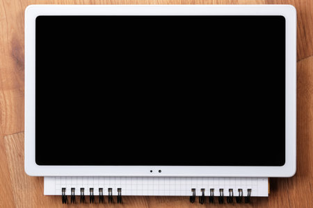 On an open tear-off notebook for notes, sheets of paper in a box, lies a switched off tablet with a...