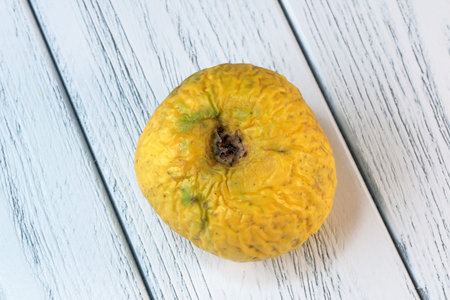 Wrinkled spoiled dried apple on a light wooden background close-up macro photography