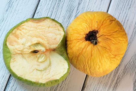 Wrinkled spoiled dried apple on a light wooden background close-up macro photographyの写真素材