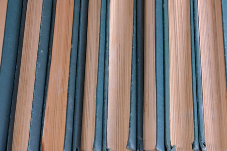 A stack of old tattered books in identical green bindings