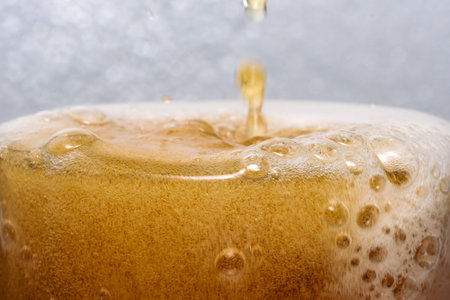 Fresh cold light beer poured into a glass to the brim close-up macro photographyの写真素材