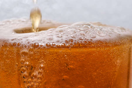 Fresh cold light beer poured into a glass to the brim close-up macro photographyの写真素材