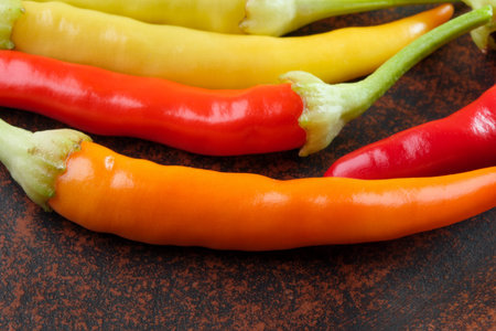 Indoor variety multicolored hot bitter pepper on a brown clay plate close-up macro photography