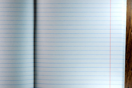 Opened blank notebook with white sheets in a ruler on a brown wooden background close-up