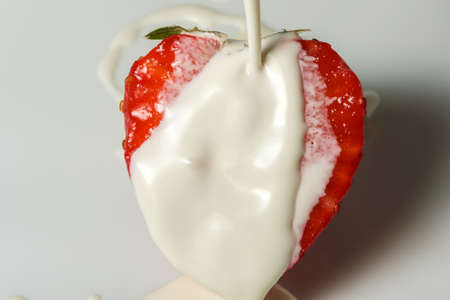 Half ripe sweet strawberries in heavy cream on berry dessert close-up macro photographyの写真素材