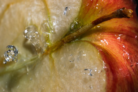 Half of a red ripe sweet apple under a stream of clean water close-up macro photography
