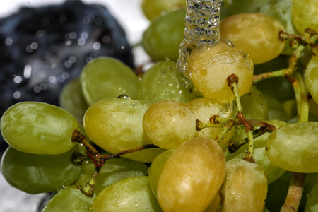 White seedless grapes in a bunch under a stream of clean water close-up macro photography