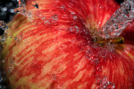 Red ripe sweet apple under a stream of clean water close-up macro photographyの写真素材