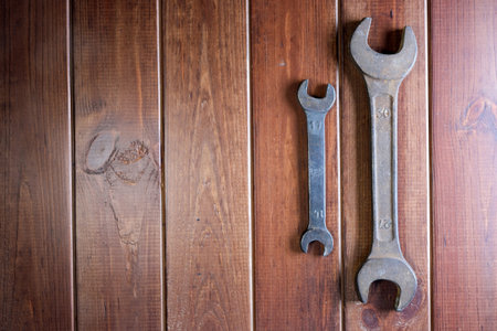 Old rusty wrenches on dark brown wooden background with place for text on the left