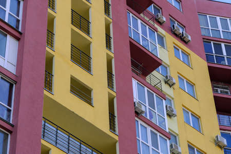 Facade of a residential modern high-rise urban house with beautiful colors on a bright summer sunny day against the blue skyの写真素材