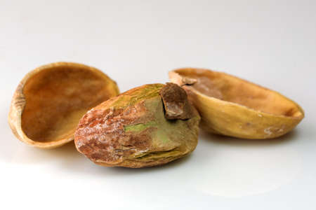Toasted salted pistachio nuts on white reflective background close-up macro photographyの写真素材