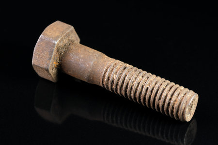 Old used bolt on black mirrored background close-up macro photography