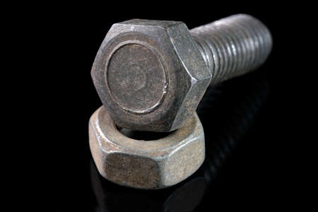 Old used bolt and nut on black mirror background close-up macro photographyの写真素材