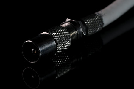 Coaxial TV cable plug on black mirrored background close-up macro photography