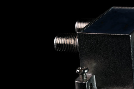 Splitter of coaxial television cable to two outputs on a black mirror background close-up macro...
