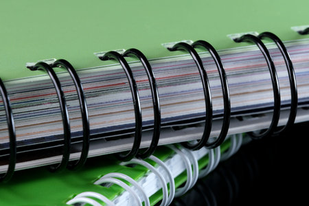 Tear-off notebooks for notes with a spiral binding on a black mirrored background in a green cover,...