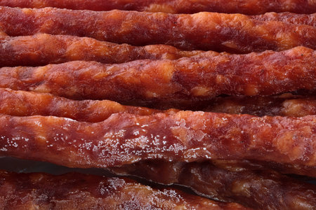 Dry smoked sausage thin sticks full screen close up food backgroundの写真素材
