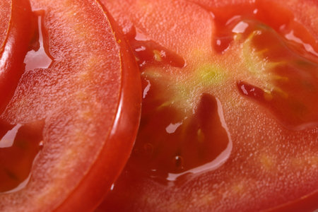 Sliced round slices of ripe red tomato close-up macro photography vegetable background