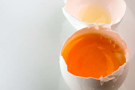 Broken chicken egg with yolk on a white background close-upの写真素材